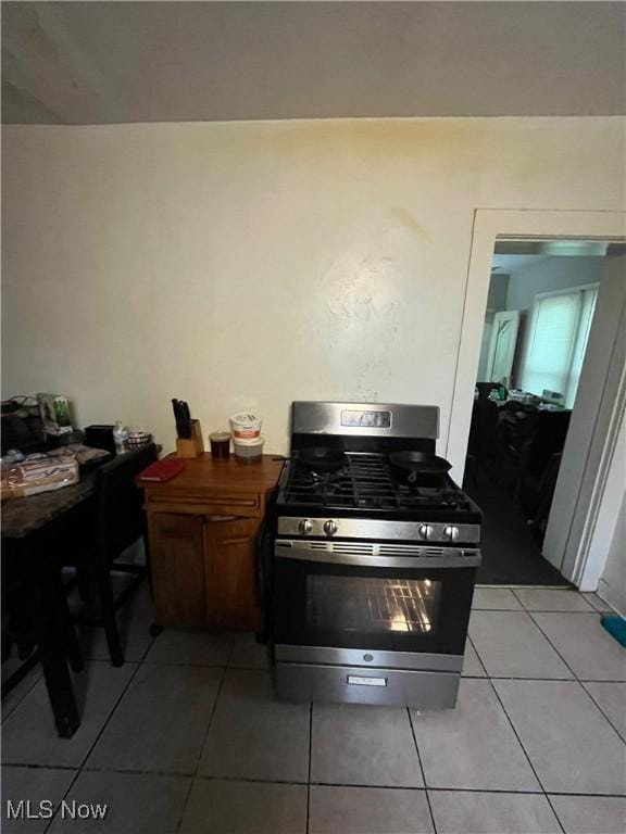 kitchen with stainless steel gas range oven and light tile patterned floors