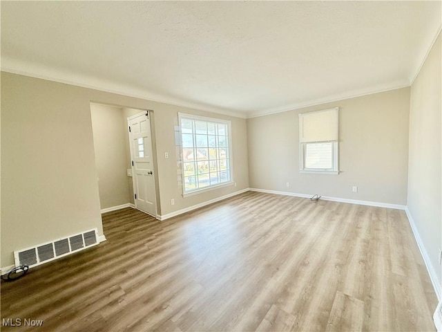 empty room featuring ornamental molding and light wood-type flooring