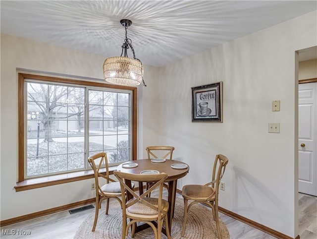 dining room featuring a healthy amount of sunlight, light hardwood / wood-style flooring, and a notable chandelier