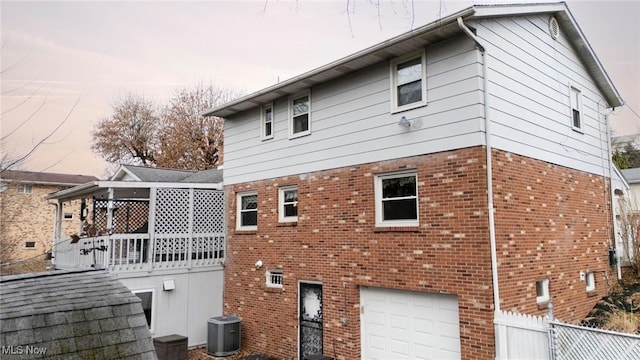 back house at dusk with a garage and central air condition unit