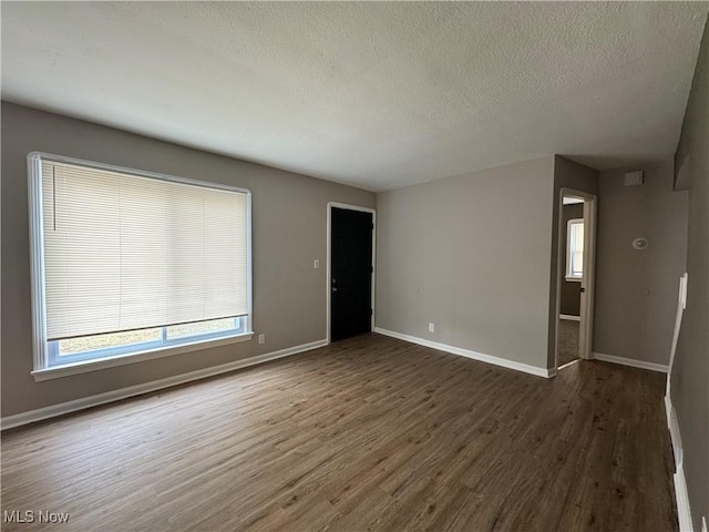 spare room with dark hardwood / wood-style floors and a textured ceiling