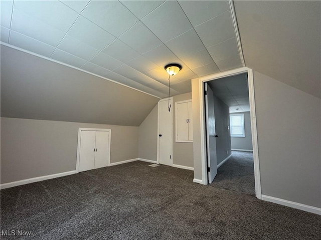 additional living space with vaulted ceiling and dark colored carpet