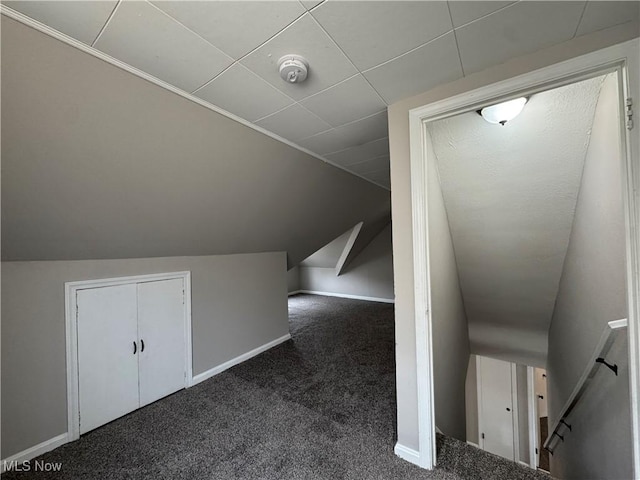 additional living space featuring vaulted ceiling and dark colored carpet