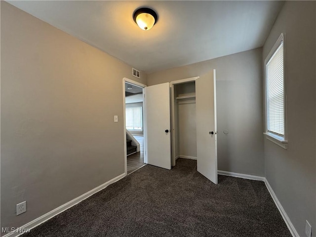 unfurnished bedroom featuring dark carpet and a closet