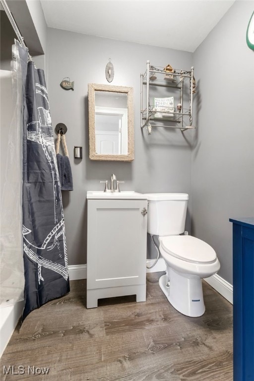 bathroom with wood-type flooring, toilet, curtained shower, and vanity