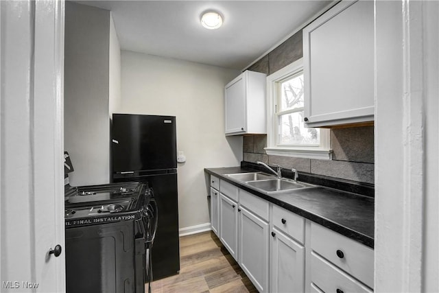 kitchen featuring sink, white cabinetry, light hardwood / wood-style flooring, decorative backsplash, and black appliances