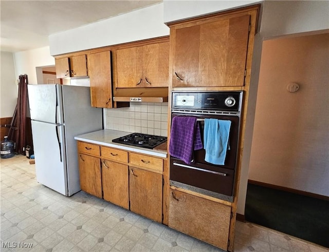 kitchen with tasteful backsplash, refrigerator, and black gas cooktop