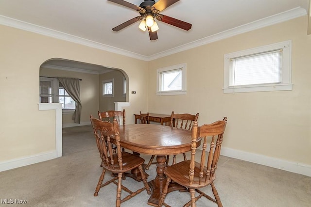 dining room with light carpet, ornamental molding, and a healthy amount of sunlight