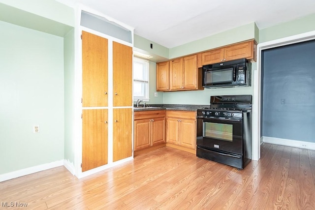 kitchen featuring sink, light hardwood / wood-style flooring, and black appliances