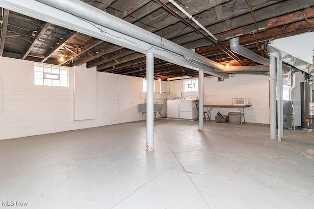 basement with washer and clothes dryer, sink, heating unit, and a wealth of natural light