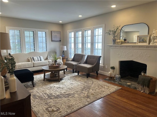 living area featuring a fireplace with flush hearth, baseboards, wood finished floors, and recessed lighting