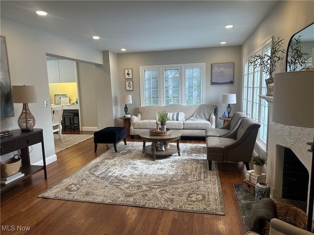 living area featuring a high end fireplace, dark wood finished floors, baseboards, and recessed lighting