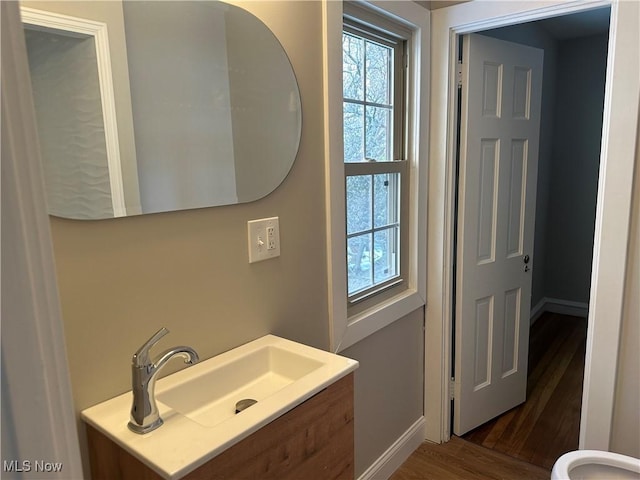 bathroom with wood finished floors, vanity, and baseboards