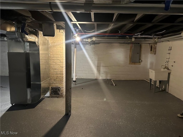 unfinished basement featuring heating unit, electric panel, and a sink