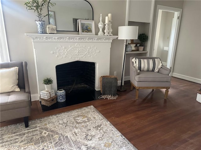 sitting room featuring a fireplace, wood finished floors, and baseboards