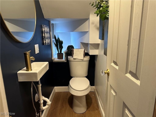 half bathroom featuring toilet, baseboards, and wood finished floors