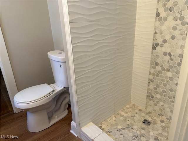 full bathroom with a stall shower, toilet, and wood finished floors