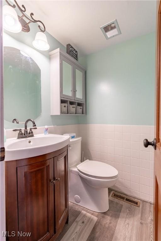 bathroom featuring hardwood / wood-style flooring, vanity, toilet, and tile walls