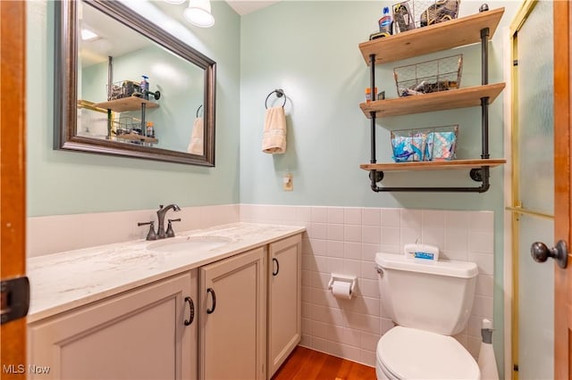 bathroom with vanity, toilet, hardwood / wood-style floors, and tile walls