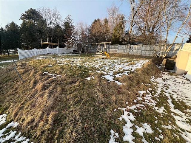 yard layered in snow with a playground