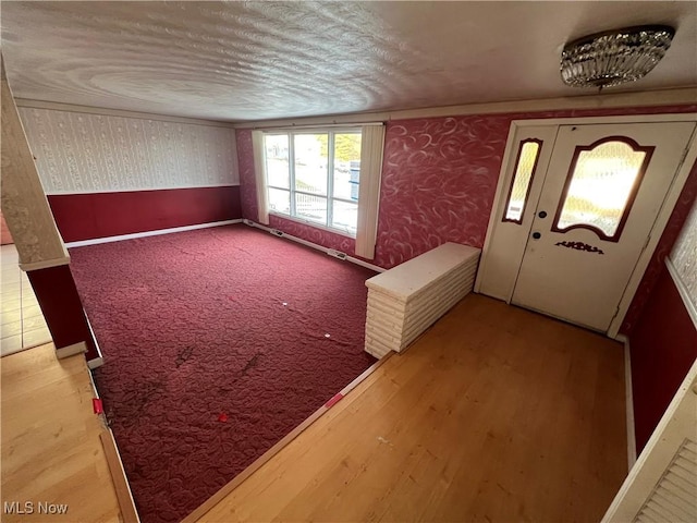 foyer with ornamental molding and carpet flooring