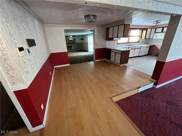 kitchen featuring ceiling fan, sink, and light wood-type flooring