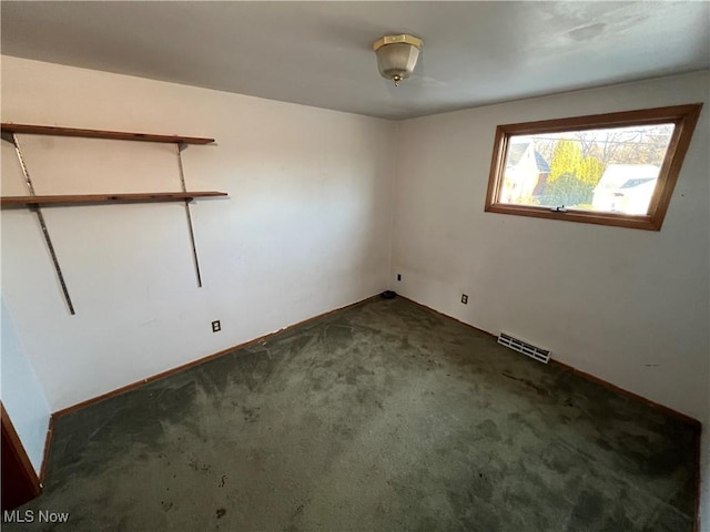 spare room featuring dark colored carpet