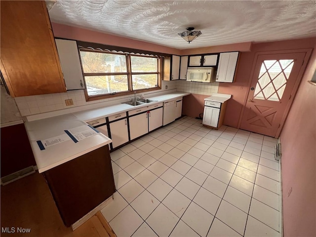 kitchen with sink, tasteful backsplash, white cabinetry, a textured ceiling, and light tile patterned floors