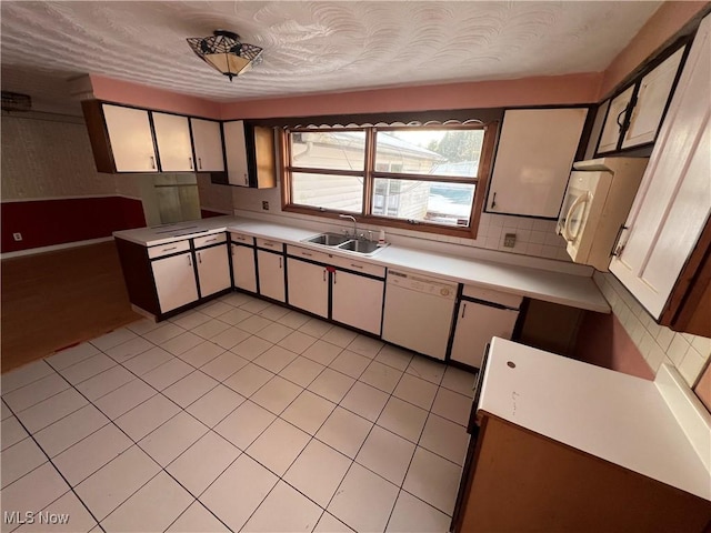 kitchen with light tile patterned flooring, sink, white cabinetry, white appliances, and decorative backsplash