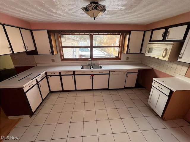 kitchen featuring sink, white cabinets, white dishwasher, and decorative backsplash