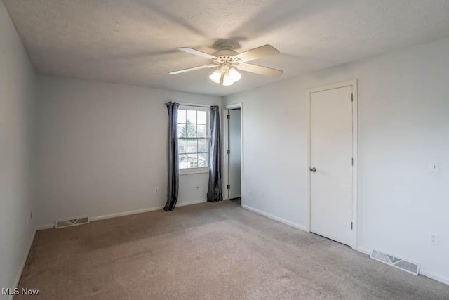 carpeted empty room featuring ceiling fan and a textured ceiling