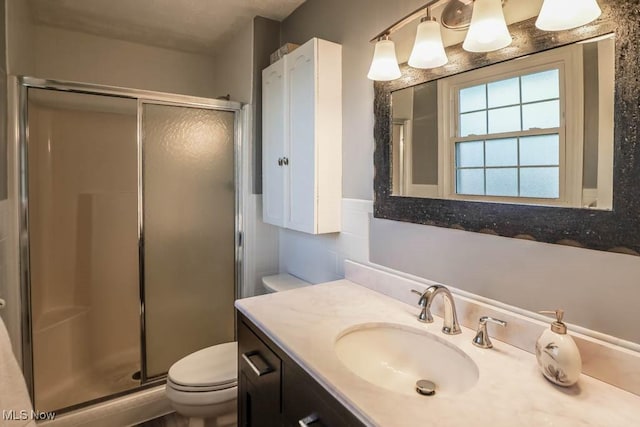 bathroom featuring vanity, a shower with shower door, and toilet