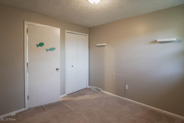 unfurnished bedroom with a closet, light carpet, and a textured ceiling