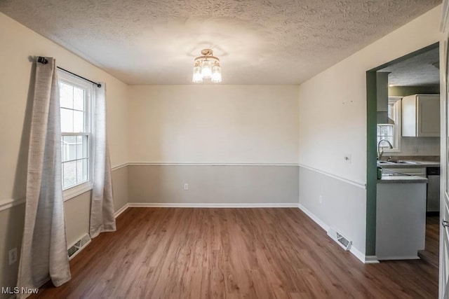 unfurnished dining area with sink, hardwood / wood-style flooring, and a textured ceiling