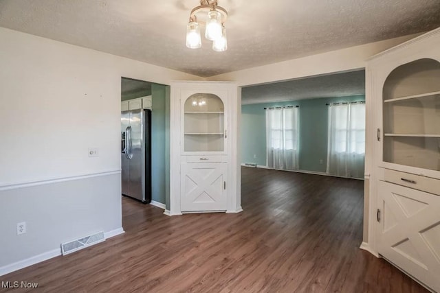 unfurnished dining area with built in shelves, dark hardwood / wood-style flooring, and a textured ceiling