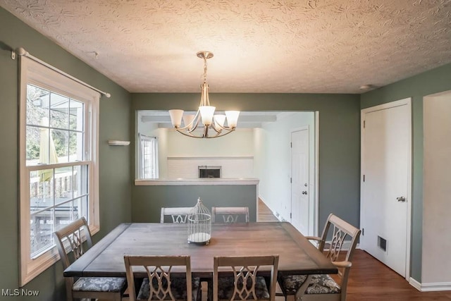 dining space with hardwood / wood-style floors, a textured ceiling, and a chandelier