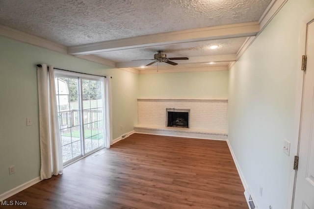 unfurnished living room featuring a brick fireplace, beam ceiling, wood-type flooring, and a textured ceiling