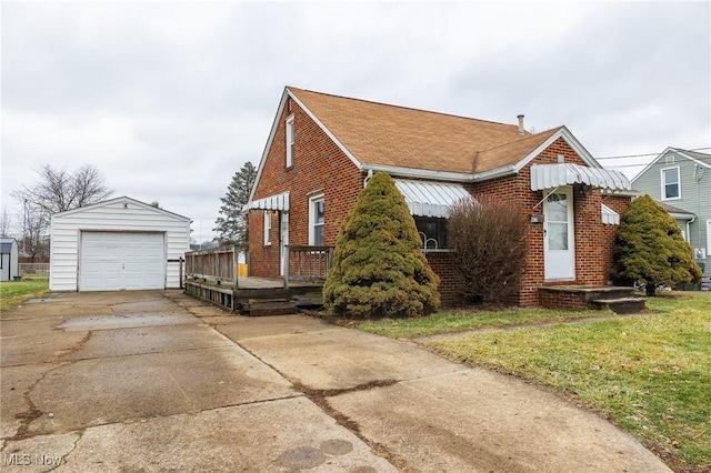 bungalow-style home with a garage, an outdoor structure, and a front yard