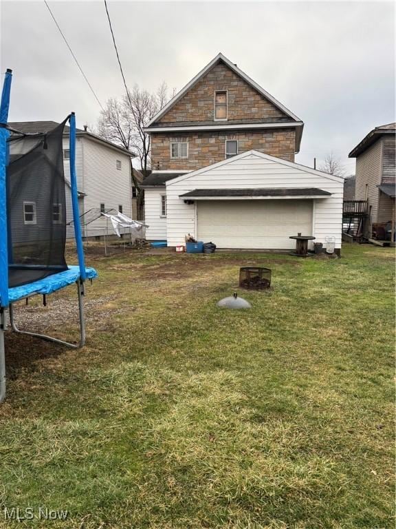 back of property featuring a yard and a trampoline