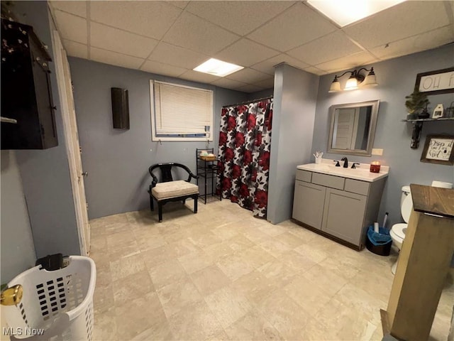 bathroom featuring vanity, toilet, a shower with shower curtain, and a drop ceiling