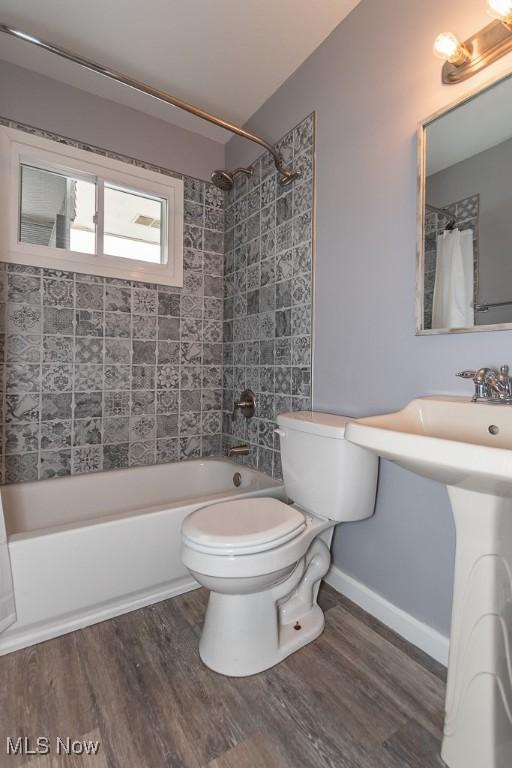 bathroom with shower / tub combo, wood-type flooring, and toilet