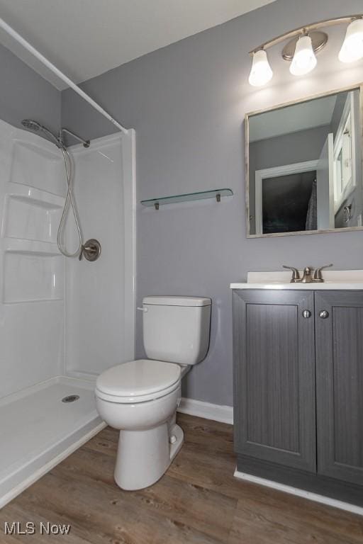 bathroom with hardwood / wood-style flooring, vanity, toilet, and a shower