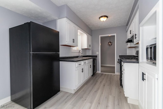 kitchen with black fridge, white cabinetry, gas range oven, and light wood-type flooring