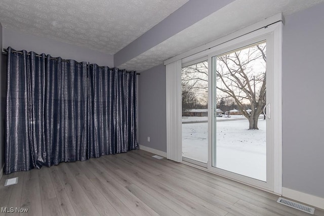 empty room with light hardwood / wood-style floors and a textured ceiling