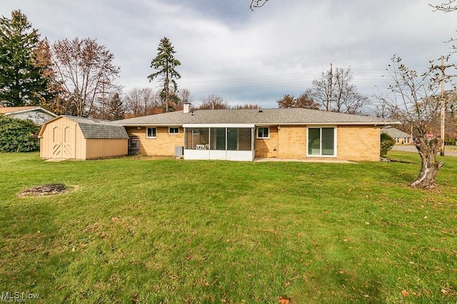 back of house featuring a yard, a sunroom, and a storage unit