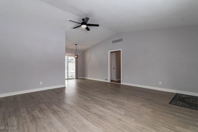 empty room with lofted ceiling, hardwood / wood-style flooring, and ceiling fan with notable chandelier