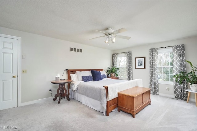 bedroom featuring ceiling fan, light colored carpet, and a textured ceiling