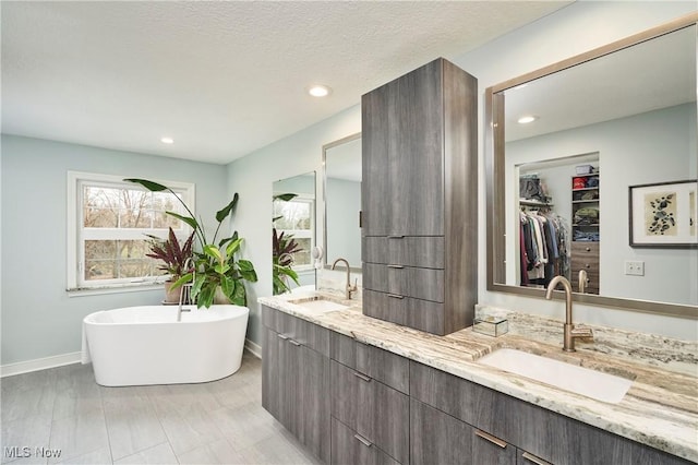 bathroom featuring vanity, a textured ceiling, and a tub