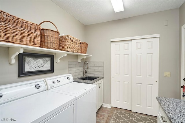 laundry area featuring cabinets, separate washer and dryer, sink, and a textured ceiling