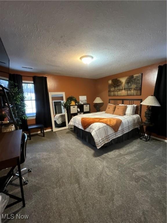 bedroom with a textured ceiling and dark colored carpet